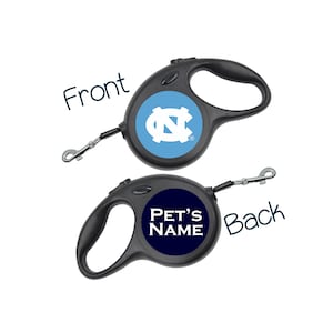 May include: A black retractable dog leash with a blue and white UNC Tar Heels logo on the front and the text "PET'S NAME" on the back.