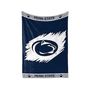 Puede incluir: Manta azul marino con el logotipo de los Nittany Lions de Penn State en blanco. La manta tiene un diseño de pincelada blanca y las palabras "PENN STATE" en blanco. Ribete gris con huellas de patas acentúa la parte superior e inferior.
