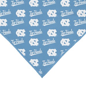 May include: A blue bandana with a white repeated pattern of the University of North Carolina Tar Heels logo and the words "Tar Heels".