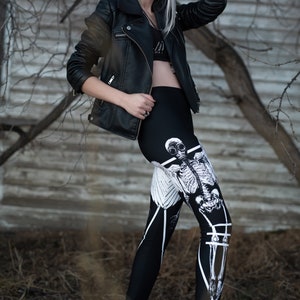 May include: A woman with silver hair wearing a black leather jacket and black leggings with a white skeleton graphic print.