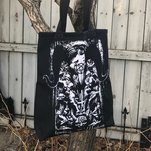 May include: Black tote bag with a white graphic print of a horned figure with a pentagram and the number 666. The text "Loais" and "Magnon" are printed at the bottom of the bag.