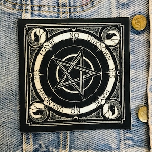 May include: Black and white square patch featuring a pentagram design. The patch has the words "YES", "NO", "MAYBE", and "UNKNOWN" around the edges. The patch is sewn onto a denim jacket.