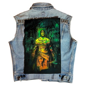 May include: A green and orange Frankenstein monster patch on a blue denim vest. The patch features a monster with stitches and a belt, sitting on a chair in a laboratory setting.