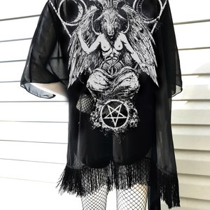 May include: Black sheer kimono with a white print of a goat-headed figure with wings and a pentagram. The kimono has black fringe around the bottom.