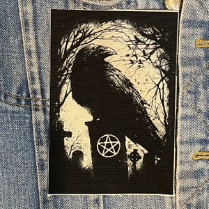 Könnte beinhalten: Schwarz-weiß gestickter Patch mit einem Raben, der auf einem Grabstein mit einem Pentagramm-Symbol sitzt. Der Rabe ist vor einem Hintergrund aus Bäumen und einem Friedhof silhouettiert.