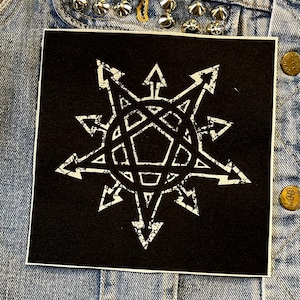 Op de afbeelding: Zwart-witte strijkpatch met een wit stervormig ontwerp op een zwarte achtergrond. De ster heeft een pentagram in het midden.