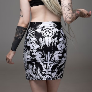 May include: Black and white mini skirt with a graphic print of a skull, pentagram, and cross. The skirt has the number 666 printed on the bottom.