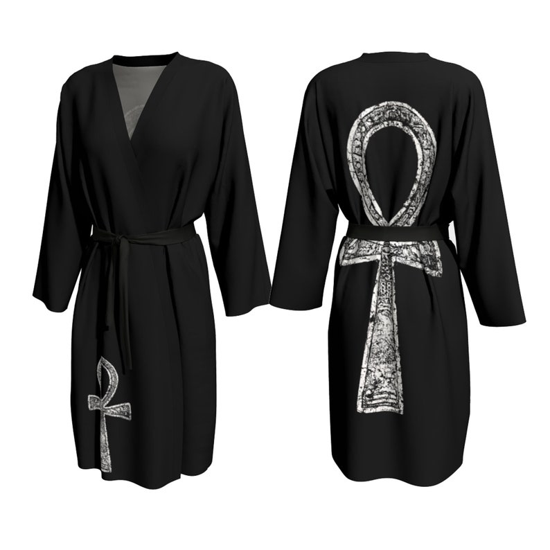 May include: Black robe with a white Ankh symbol on the back. The robe has a V-neck and long sleeves. The Ankh symbol is a stylized cross with a loop at the top.
