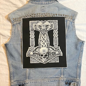 May include: A black and white patch with a detailed illustration of a Mjolnir hammer, a Norse symbol, surrounded by a Celtic knot design. The hammer is adorned with a skull and other intricate details.