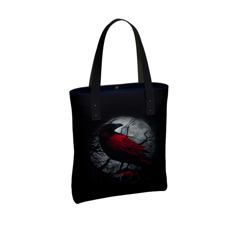 May include: Black tote bag with a red crow perched on a branch in front of a full moon. The crow has black wings and a red body.