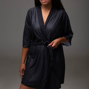May include: A black, long-sleeved robe with a shawl collar and a tie belt. The robe is made of a soft, silky fabric.