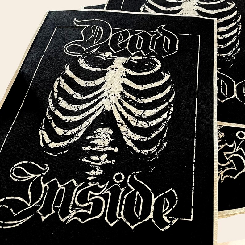 May include: Black and white patch with the text "Dead Inside" in a gothic font. A white ribcage graphic is centered on the patch.