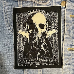 May include: Black and white embroidered patch featuring a skull with bat wings and tentacles, surrounded by an ornate frame. The text "Lewis Mayhem" is at the bottom.