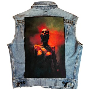 May include: A denim vest with a large patch on the back. The patch features a woman with a distressed look, screaming with her mouth open. The background is a dark red and orange with smoke.