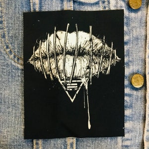 May include: Black and white embroidered patch with a stylized image of a mouth with barbed wire around it and a dripping triangle with a symbol inside.