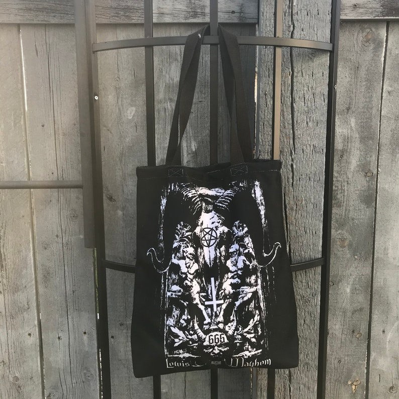 May include: Black canvas tote bag with a white graphic print of a pentagram, skull, and the text "666 Lotus Mayhem".
