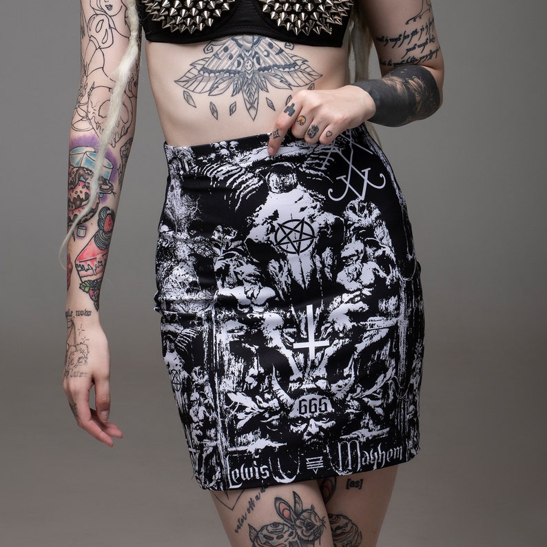 May include: Black and white mini skirt with a graphic print of a pentagram, skulls, and the words "Lewis" and "Mayhem". The skirt also has the number "666" printed on it.