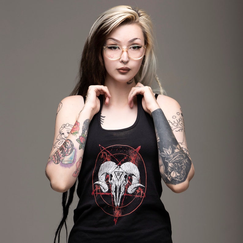 May include: A black tank top with a red pentagram and a white skull with horns graphic. The model is wearing the tank top and has long blonde hair with black dreadlocks.