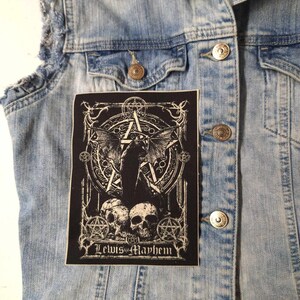 May include: Black and white embroidered patch with a pentagram, skulls, and a winged figure. The patch has the text "Lewis Mayhem" at the bottom.