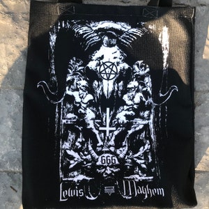 May include: Black tote bag with a white graphic print of a skull with horns, a pentagram, and a cross. The text "Lewis  Mayhem" and "666" are also printed on the bag.