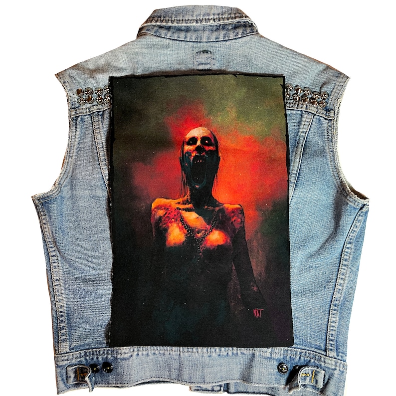 May include: A denim vest with a large patch on the back. The patch features a woman with a screaming expression, set against a red and orange background.