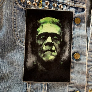 Peut inclure: Un patch brodé noir et vert représentant un gros plan du visage de Frankenstein.