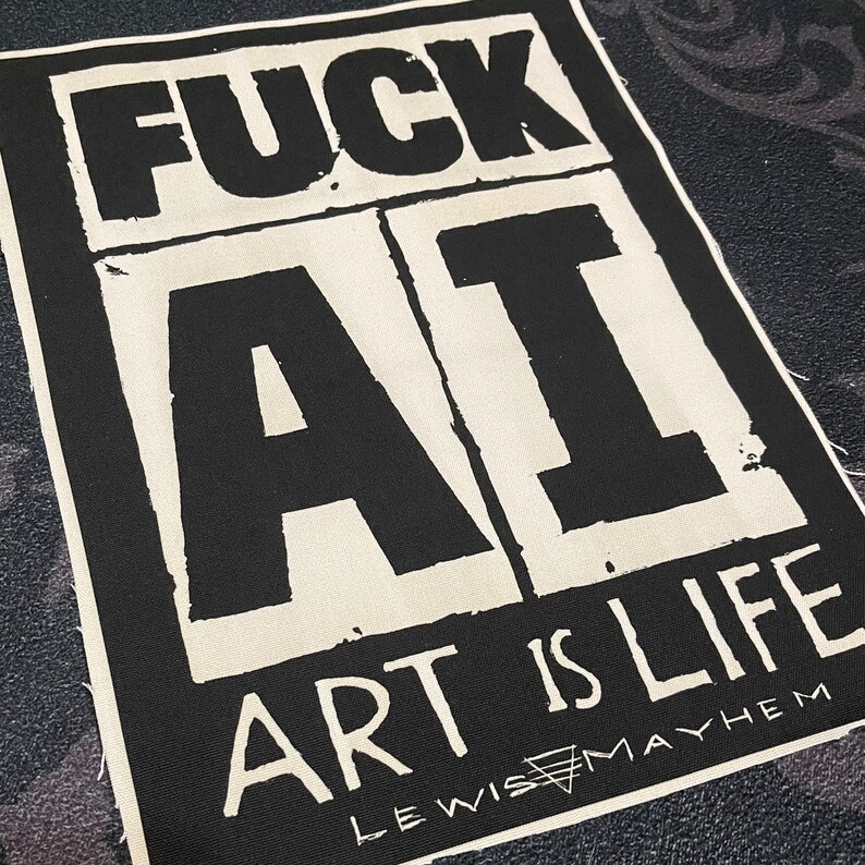 May include: Black and white patch with the text "FUCK AI ART IS LIFE" and the text "LEWIS MAYHEM" in a smaller font below.