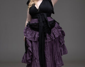 May include: A woman wearing a black hooded top and a long, purple, ruffled skirt. The skirt has a black waistband and is asymmetrical.