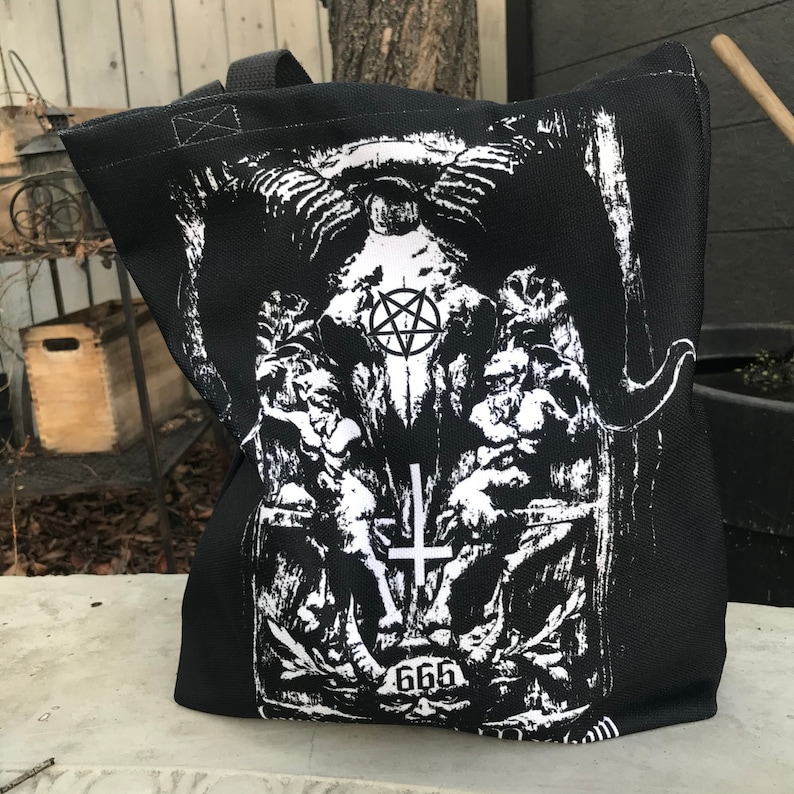 May include: Black tote bag with a white graphic print of a skull with horns, a pentagram, and the number 666.