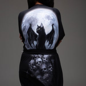 May include: Black and white robe with a full moon and a black cat with wings on the back. The bottom of the robe has a skull pattern.
