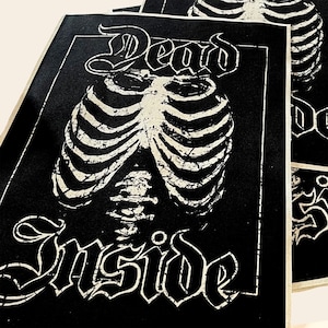 May include: Black and white patch with the text "Dead Inside" in a gothic font. A white ribcage graphic is centered on the patch.