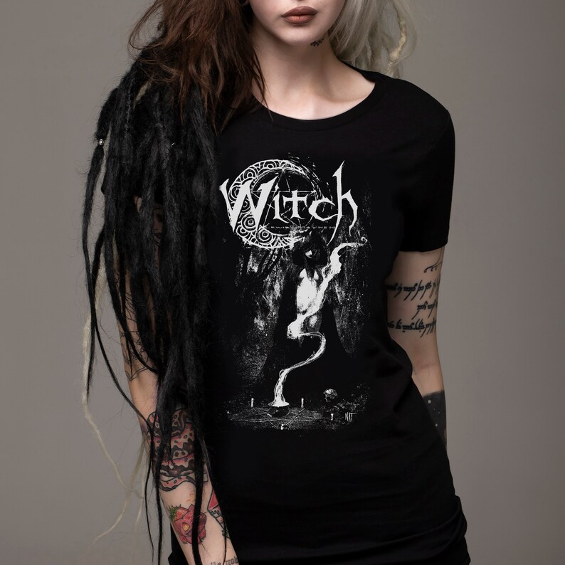 May include: Black t-shirt with a white graphic print of a witch with the word "Witch" above her. The graphic is surrounded by a crescent moon and a circle of decorative elements.