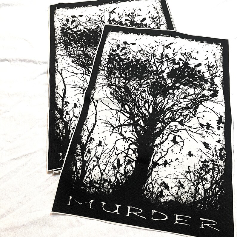 K&ouml;nnte beinhalten: Schwarz-wei&szlig;es B&uuml;geleisen-Patch mit der Silhouette eines Baumes, um den herum V&ouml;gel fliegen. Der Text "MURDER" ist unten auf dem Patch aufgedruckt.