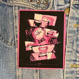 May include: Pink and black iron-on patch featuring a graphic of multiple mouths screaming and a fist with the words "Riot Grail" and "Lewis Machine" in white text.