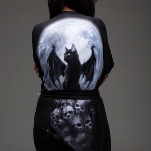 May include: Black robe with a full moon and a black cat with wings printed on the back. The bottom of the robe has a print of a pile of skulls.