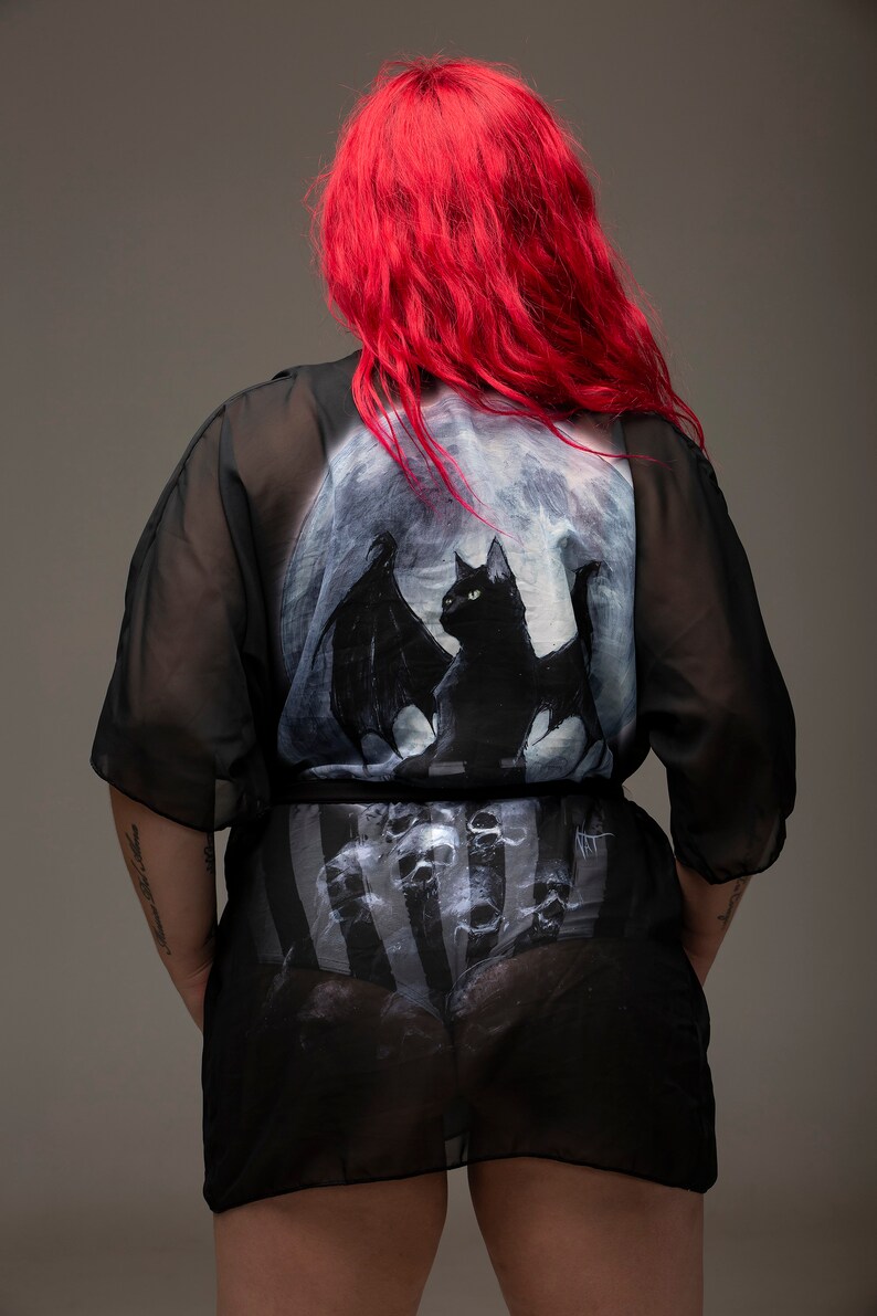 May include: Black sheer robe with a bat and moon print. The robe has a striped pattern underneath.