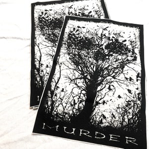 K&ouml;nnte beinhalten: Schwarz-wei&szlig; Patch mit einer gro&szlig;en Baum-Silhouette und vielen V&ouml;geln, die um sie herum fliegen. Der Text "MURDER" ist am unteren Rand des Patches gedruckt.
