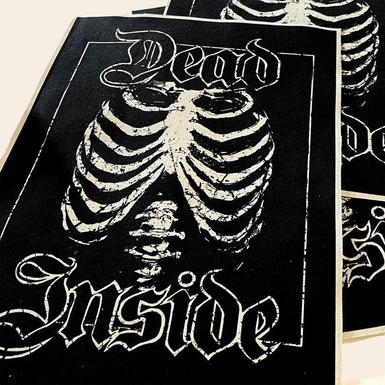 May include: Black and white patch with the text "Dead Inside" in a gothic font. A white ribcage graphic is centered on the patch.