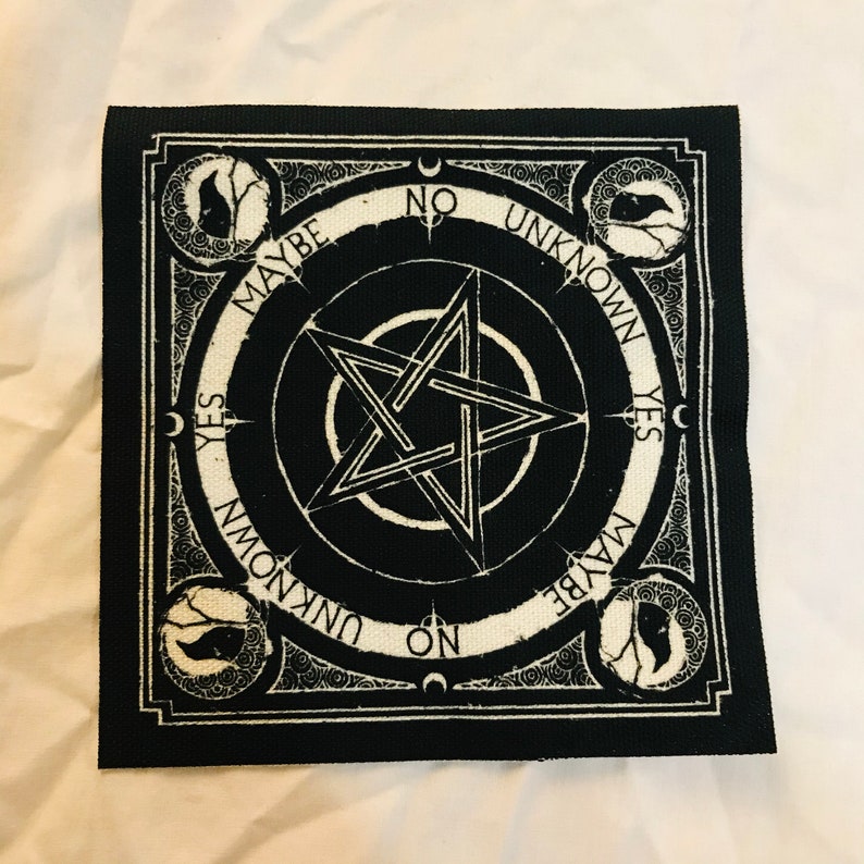May include: Black and white square patch with a pentagram design at the center. The patch features the words "YES", "NO", "MAYBE", and "UNKNOWN" around the pentagram. Decorative elements include crescent moons and stylized tree and bird illustrations.
