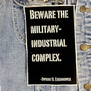 May include: Black and white patch with the text "Beware the Military-Industrial Complex."  -Dwight D. Eisenhower