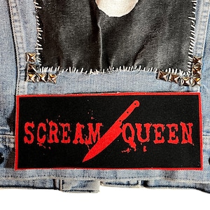 Peut inclure: Patch noir avec du texte rouge et un graphique de couteau rouge qui dit "Scream Queen".