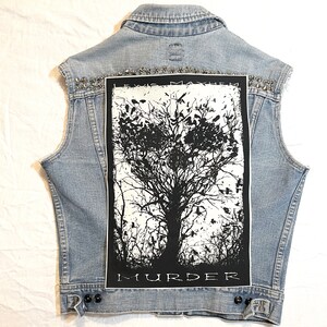 K&ouml;nnte beinhalten: Eine hellblaue Jeansweste mit einem schwarzen und wei&szlig;en Patch auf der R&uuml;ckseite. Der Patch zeigt einen Baum mit V&ouml;geln und den Text "Lewis Mayhem Murder".