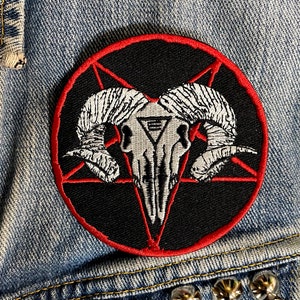 May include: A black and red embroidered patch featuring a white ram skull within a pentagram.