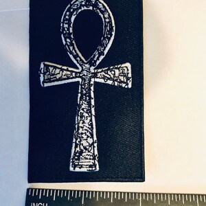 Puede incluir: Parche de tela negro con un s&iacute;mbolo Ankh bordado en blanco. El parche mide aproximadamente 5 cm de ancho.