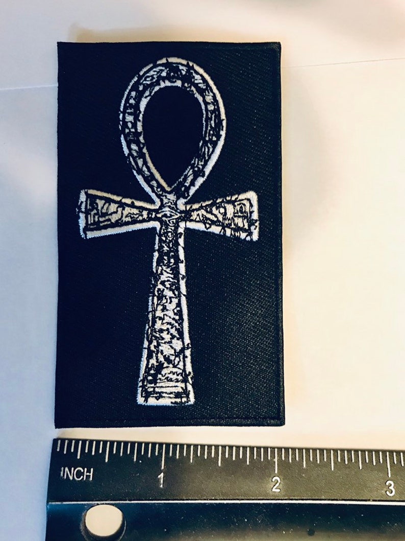 Puede incluir: Parche de tela negro con un s&iacute;mbolo Ankh bordado en blanco. El parche mide aproximadamente 5 cm de ancho.