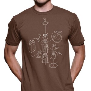 Può includere: Una maglietta marrone con un contorno bianco di una caffettiera a pistone, che mostra i singoli pezzi e i passaggi numerati per il montaggio. Il testo "1.  2.  3.  4.  5.  6.  7.  8.  9.  10.  11.  12.  13.  14.  15.  16.  17.  18.  19.  20.  21.  22.  23.  24.  25." è stampato sulla maglietta.