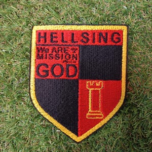 May include: Embroidered patch with a shield design. The top section reads "HELLSING" in black letters on a red background. The lower section has the words "We ARE MISSION GOD" and a castle tower graphic.