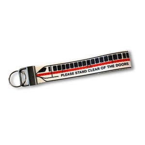 May include: A white keychain wrist strap with a black and red train design. The strap has the text "PLEASE STAND CLEAR OF THE DOORS" printed in black. The keychain has a silver metal clasp and key ring.