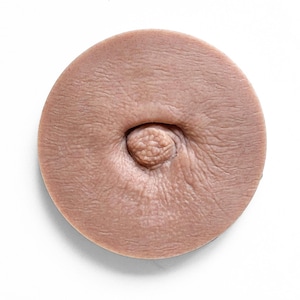 May include: A close-up of a round, flesh-toned silicone mould with a raised nipple in the centre.