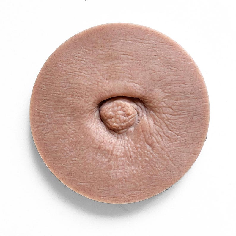 May include: A close-up of a round, flesh-toned silicone mould with a raised nipple in the centre.